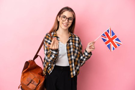 Téléchargez les photos : Jeune femme hispanique tenant un drapeau britannique isolé sur fond rose invitant à venir avec la main. Heureux que tu sois venu - en image libre de droit