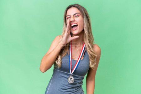 Photo for Young pretty sport Uruguayan woman with medals over isolated background shouting with mouth wide open - Royalty Free Image