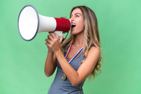 Photo for Young pretty sport Uruguayan woman with medals over isolated background shouting through a megaphone - Royalty Free Image