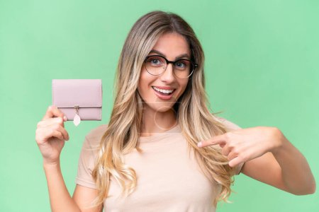 Photo for Young Uruguayan woman holding a wallet over isolated background with surprise facial expression - Royalty Free Image