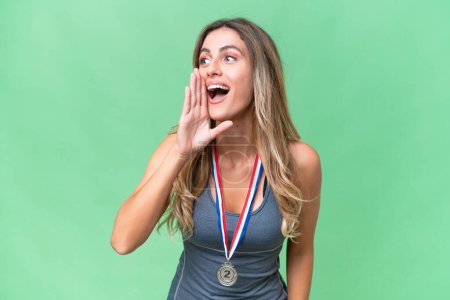 Photo for Young pretty sport Uruguayan woman with medals over isolated background shouting with mouth wide open to the lateral - Royalty Free Image