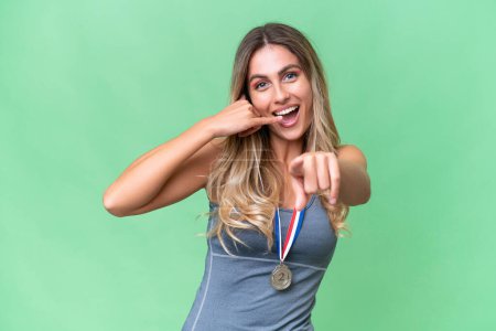 Photo for Young pretty sport Uruguayan woman with medals over isolated background making phone gesture and pointing front - Royalty Free Image