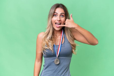 Photo for Young pretty sport Uruguayan woman with medals over isolated background making phone gesture. Call me back sign - Royalty Free Image