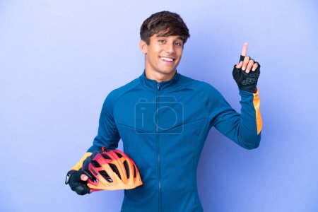 Photo for Young cyclist caucasian man isolated on purple background pointing up a great idea - Royalty Free Image