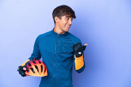 Photo for Young cyclist caucasian man isolated on purple background pointing to the side to present a product - Royalty Free Image