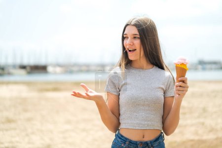 Téléchargez les photos : Adolescente avec une crème glacée cornet à l'extérieur avec expression faciale surprise - en image libre de droit