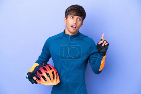 Photo for Young cyclist caucasian man isolated on purple background thinking an idea pointing the finger up - Royalty Free Image
