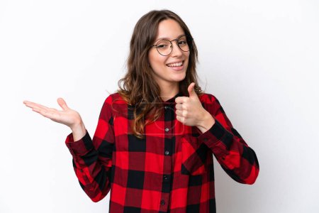 Photo for Young caucasian woman isolated on white background holding copyspace imaginary on the palm to insert an ad and with thumbs up - Royalty Free Image