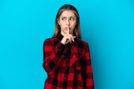 Photo for Young caucasian woman isolated on blue background showing a sign of silence gesture putting finger in mouth - Royalty Free Image
