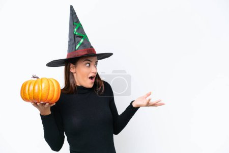 Photo for Young caucasian woman costume as witch holding a pumpkin isolated on white background with surprise facial expression - Royalty Free Image