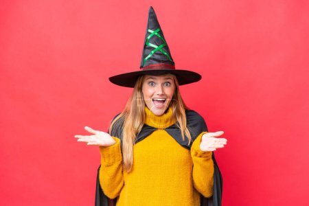 Photo for Young caucasian woman costume as witch isolated on red background with shocked facial expression - Royalty Free Image