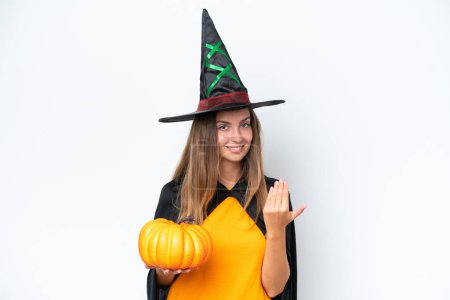Photo for Young caucasian woman costume as witch holding a pumpkin isolated on white background inviting to come with hand. Happy that you came - Royalty Free Image