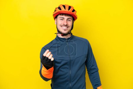 Téléchargez les photos : Jeune cycliste caucasien homme isolé sur fond jaune faire geste d'argent - en image libre de droit