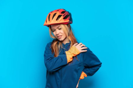 Téléchargez les photos : Jeune cycliste fille isolée sur fond bleu souffrant de douleur à l'épaule pour avoir fait un effort - en image libre de droit