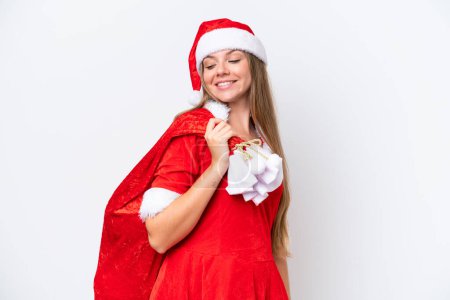Foto de Joven mujer caucásica vestida como mamá noel sosteniendo saco de Navidad aislado sobre fondo blanco con expresión feliz - Imagen libre de derechos