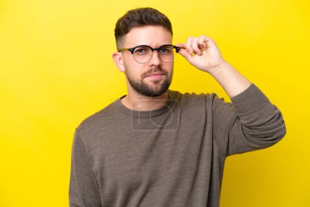 Photo for Young caucasian man isolated on yellow background With glasses and frustrated expression - Royalty Free Image