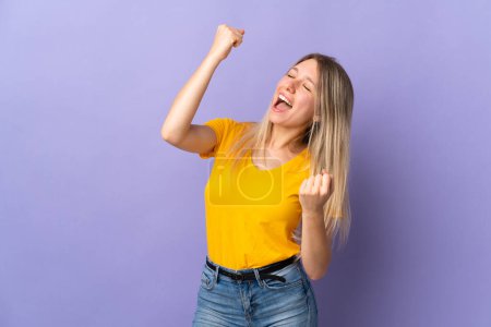 Téléchargez les photos : Jeune femme blonde isolée sur fond violet célébrant une victoire - en image libre de droit