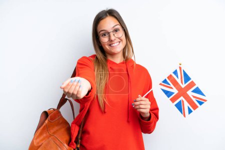 Téléchargez les photos : Jeune femme hispanique tenant un drapeau britannique isolé sur fond blanc invitant à venir avec la main. Heureux que tu sois venu - en image libre de droit