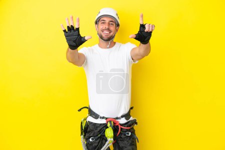 Téléchargez les photos : Jeune grimpeur isolé sur fond jaune comptant sept doigts - en image libre de droit