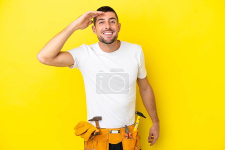 Photo for Young electrician caucasian man isolated on yellow background looking far away with hand to look something - Royalty Free Image