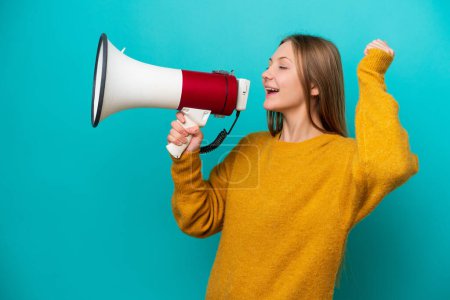 Photo for Young Russian woman isolated on blue background shouting through a megaphone to announce something in lateral position - Royalty Free Image
