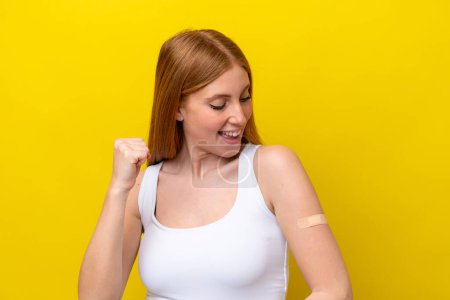 Photo for Young redhead woman wearing a band-aids isolated on yellow background celebrating a victory - Royalty Free Image