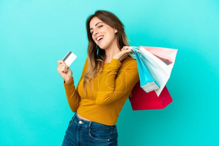 Téléchargez les photos : Femme blanche isolée sur fond bleu tenant des sacs à provisions et une carte de crédit - en image libre de droit