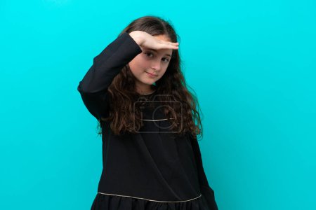 Photo for Little girl isolated on blue background looking far away with hand to look something - Royalty Free Image