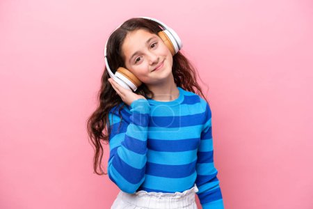 Téléchargez les photos : Petite fille isolée sur fond rose écoutant de la musique - en image libre de droit
