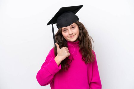 Foto de Niña estudiante usando un sombrero graduado aislado sobre fondo rosa con los pulgares hacia arriba porque algo bueno ha sucedido - Imagen libre de derechos