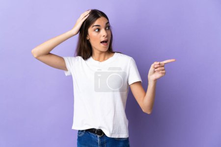 Photo for Young caucasian woman isolated on blue background surprised and pointing finger to the side - Royalty Free Image