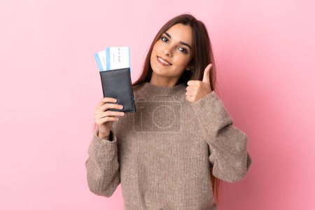 Photo for Young caucasian woman isolated on pink background in vacation holding a passport and plane with thumb up - Royalty Free Image
