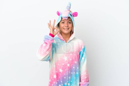 Foto de Niña con pijama de unicornio aislado sobre fondo blanco mostrando signo aceptable con los dedos - Imagen libre de derechos