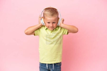 Foto de Pequeño chico ruso escuchando música con auriculares sobre un fondo aislado - Imagen libre de derechos