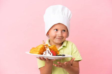 Photo for Little Russian boy holding waffles over isolated background - Royalty Free Image