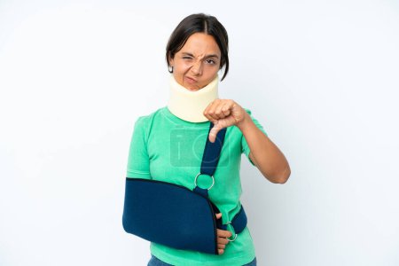 Photo for Young hispanic woman wearing a neck brace and sling isolated on white background showing thumb down with negative expression - Royalty Free Image