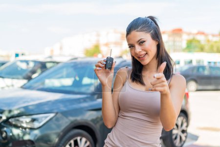 Photo for Young pretty woman holding car keys at outdoors points finger at you with a confident expression - Royalty Free Image