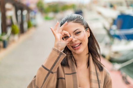 Téléchargez les photos : Jeune jolie femme à l'extérieur Avec des lunettes avec une expression heureuse - en image libre de droit