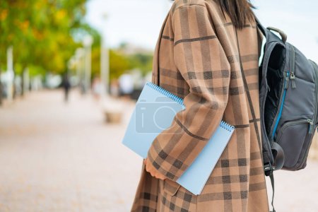 Photo for Young pretty woman at outdoors holding a notebook - Royalty Free Image