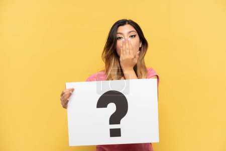 Photo for Young Russian girl isolated on yellow background holding a placard with question mark symbol with surprised expression - Royalty Free Image