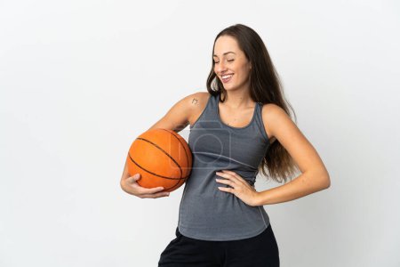 Téléchargez les photos : Jeune femme jouant au basket sur fond blanc isolé posant avec les bras à la hanche et souriant - en image libre de droit
