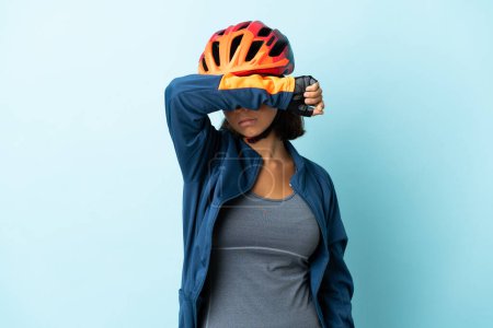 Téléchargez les photos : Jeune cycliste femme isolée sur fond bleu couvrant les yeux par les mains - en image libre de droit