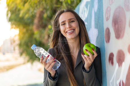 Foto de Mujer joven al aire libre con una manzana y con una botella de agua - Imagen libre de derechos