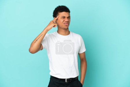 Téléchargez les photos : Jeune homme afro-américain isolé sur fond bleu faisant le geste de folie en mettant le doigt sur la tête - en image libre de droit