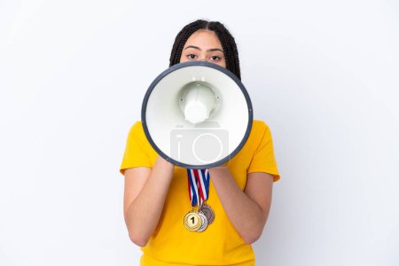 Photo for Teenager girl with braids and medals over isolated pink background shouting through a megaphone - Royalty Free Image