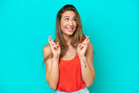 Photo for Young caucasian woman isolated on blue background with fingers crossing and wishing the best - Royalty Free Image