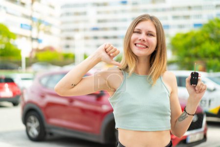 Foto de Joven mujer rubia sosteniendo las llaves del coche al aire libre orgullosa y satisfecha - Imagen libre de derechos