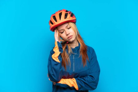 Téléchargez les photos : Jeune cycliste fille isolée sur fond bleu avec mal de tête - en image libre de droit