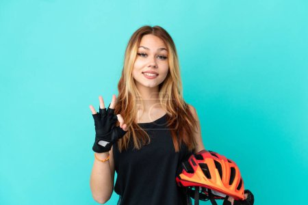 Téléchargez les photos : Jeune fille cycliste sur fond bleu isolé montrant ok signe avec deux mains - en image libre de droit