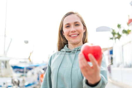 Photo for Young blonde woman with an apple at outdoors with happy expression - Royalty Free Image